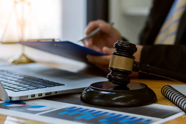 Lawyer working on papers on a table with judge's hammer and gold scales, legal concepts and consultants.